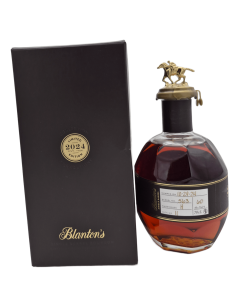 Bouteille de bourbon Blanton’s limitée année 2024 avec étiquette et bouchon cheval en or, présentée à côté d’un emballage noir.