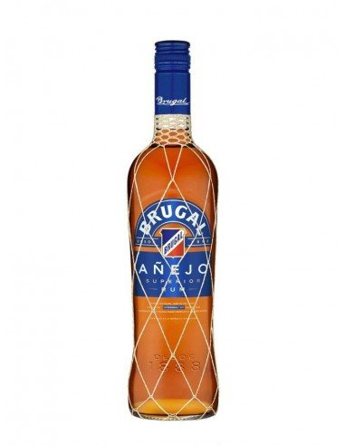 Bouteille de rhum ambré Brugal Añejo avec étiquette bleue et bouteille enveloppée d’un filet blanc.